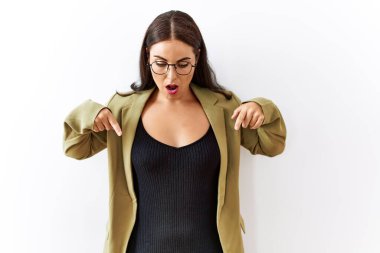 Genç esmer kadın izole edilmiş arka planda dikiliyor parmaklarını göstererek reklamını yapıyor, şaşırmış yüz ve ağzını açıyor. 