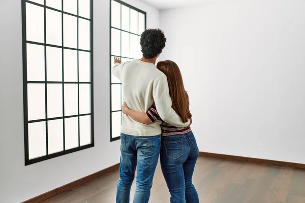 Young Hispanic Couple Back View Hugging Standing Empty New Home — Stock Photo, Image
