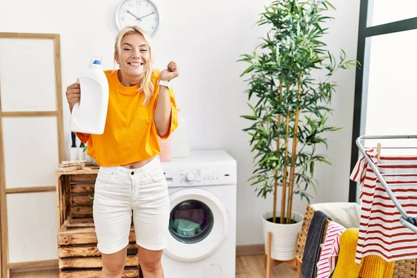Jovem Caucasiana Fazendo Lavanderia Segurando Garrafa Detergente Gritando Orgulhoso Celebrando — Fotografia de Stock