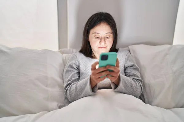 Młoda Kobieta Zespołem Downa Pomocą Smartfona Siedzi Łóżku Sypialni — Zdjęcie stockowe