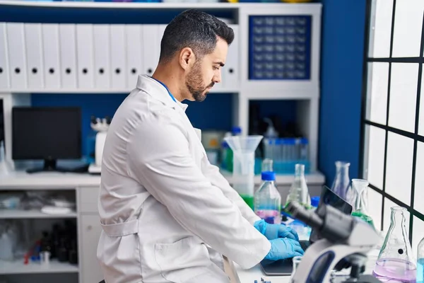 Genç İspanyol bilim adamı laboratuvarda dizüstü bilgisayar kullanıyor.