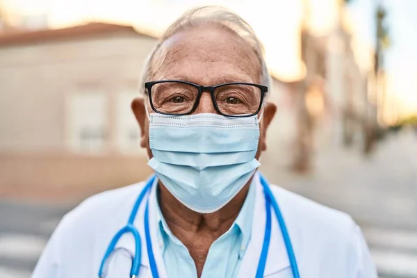 Senior man wearing doctor uniform wearing medical mask at street