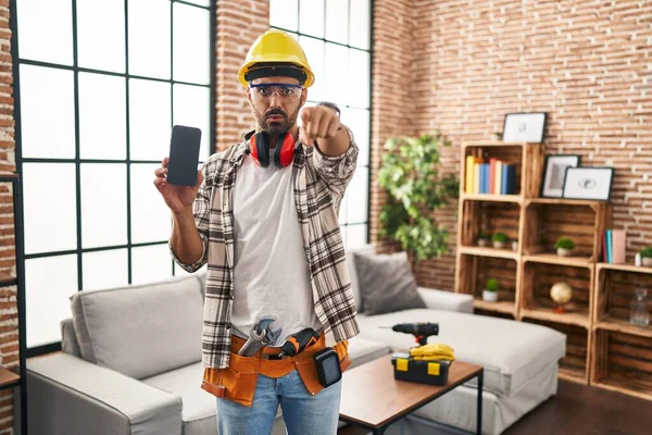Mladý Hispánec Vousy Pracujícími Renovaci Domova Drží Smartphone Ukazující Prstem — Stock fotografie