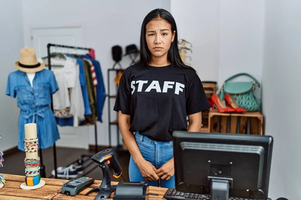 Young hispanic woman working as staff at retail boutique skeptic and nervous, frowning upset because of problem. negative person.