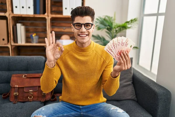 Young Hispanic Man Working Therapy Office Holding Shekels Doing Sign — Photo