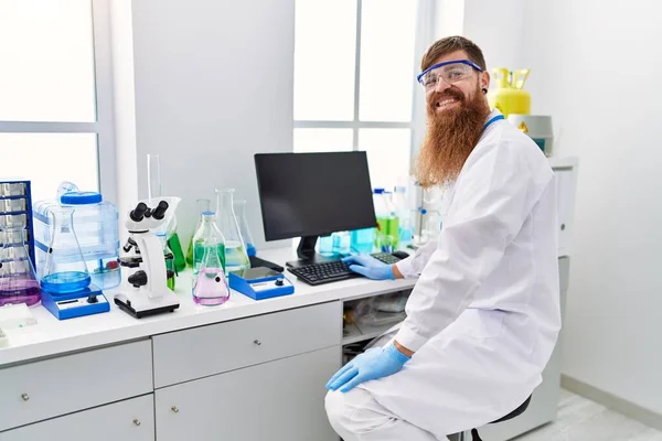 Young redhead man wearing scientist uniform working at laboratory