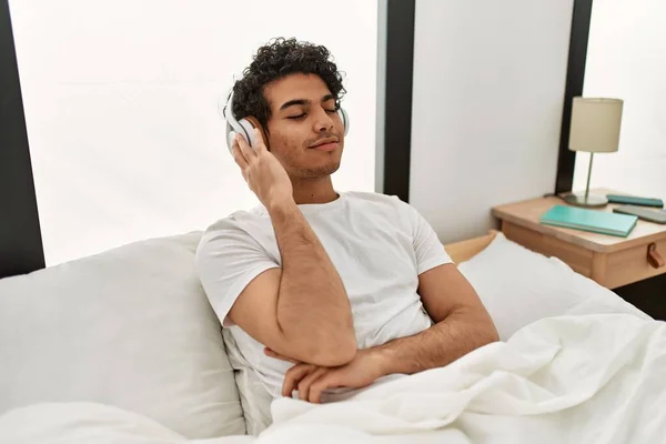 Молодий Іспаномовний Чоловік Слухає Музику Сидячи Ліжку Спальні — стокове фото