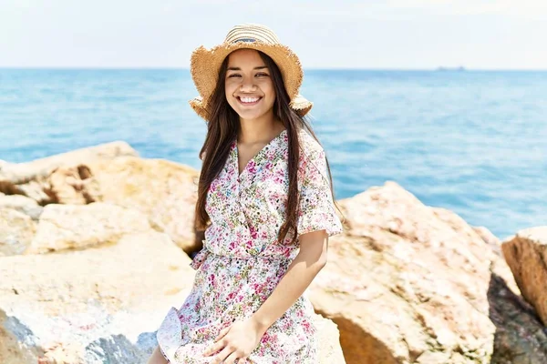 若いですラテン語の女の子身に着けています夏の帽子座っていますザ岩の上にビーチ — ストック写真