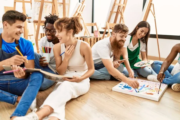 Group of people smiling happy drawing sitting on the floor at art studio.