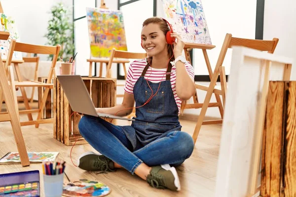 Mujer Joven Sonriendo Confiada Usando Portátil Auriculares Estudio Arte — Foto de Stock