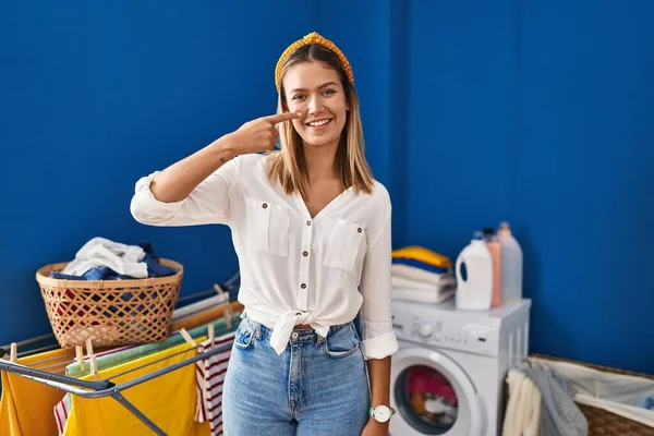 Young Blonde Woman Laundry Room Pointing Hand Finger Face Nose — Stockfoto
