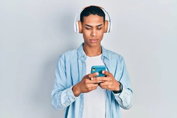 Ung Afrikansk Amerikansk Kille Med Smartphone Bär Hörlurar Tänkande Attityd — Stockfoto