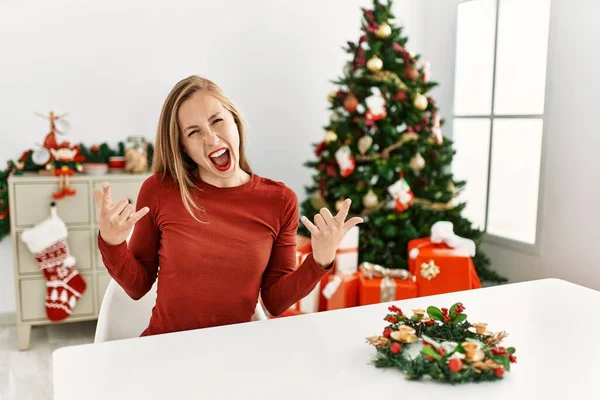 Kavkazská Mladá Blondýnka Sedící Stole Vánočního Stromku Křičící Bláznivým Výrazem — Stock fotografie