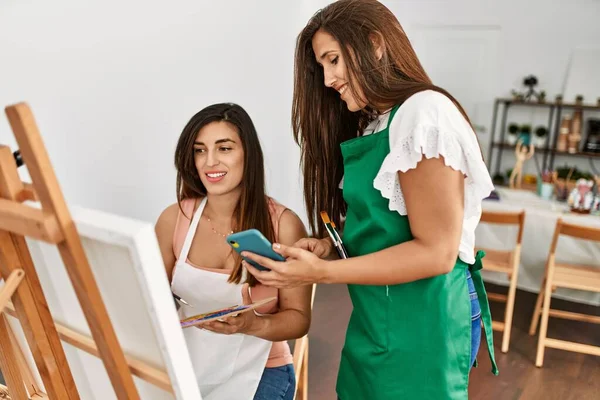在艺术学校 两名拉丁绘画学生一边笑着一边用智能手机作画 — 图库照片