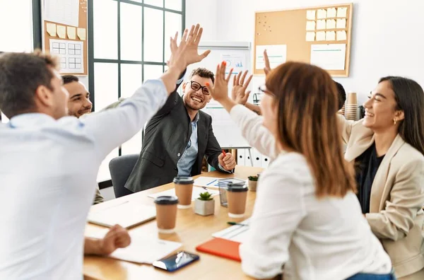 Group of business workers smiling happy celebrating high five at the office.