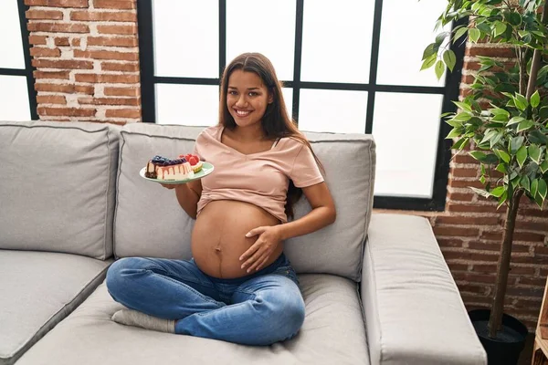 Mladý Latina Žena Těhotná Jíst Sladkosti Sedí Pohovce Doma — Stock fotografie