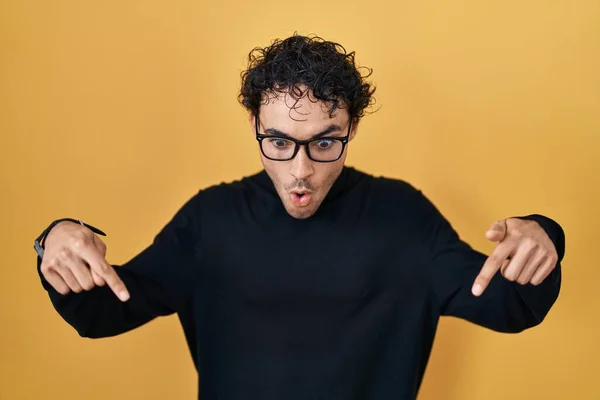 Hispanic Man Standing Yellow Background Pointing Fingers Showing Advertisement Surprised — Stok fotoğraf