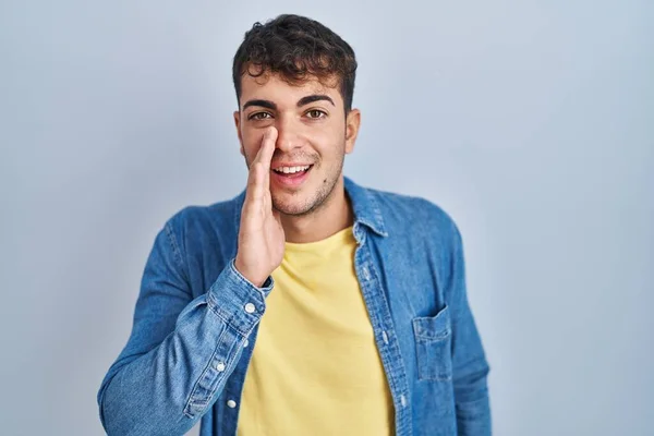 Joven Hombre Hispano Pie Sobre Fondo Azul Mano Sobre Boca — Foto de Stock