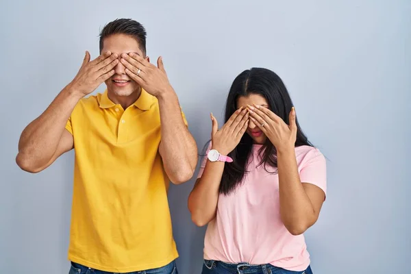 Young Couple Standing Isolated Background Covering Eyes Hands Smiling Cheerful — Stock Photo, Image