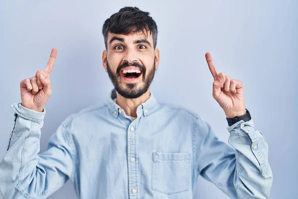 Young Hispanic Man Beard Standing Blue Background Smiling Amazed Surprised — Stockfoto