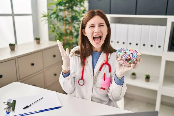 Young Doctor Woman Holding Sweets Candy Celebrating Victory Happy Smile — Stock Photo, Image