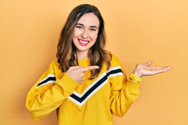 Gündelik kıyafetler giyen genç İspanyol kız kameraya hayret ediyor ve gülümsüyor.. 