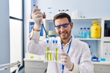 Laboratuvarda pipeti kullanarak sıvıyı ölçen genç İspanyol bilim adamı.