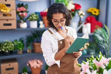 Çiçekçide defter okuyan güzel bir İspanyol kadın.