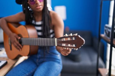 Müzik stüdyosunda klasik gitar çalan Afrikalı Amerikalı kadın müzisyen.