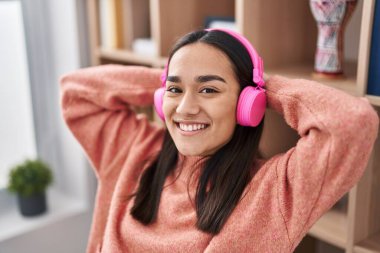 Genç İspanyol kadın evde oturmuş müzik dinliyor.