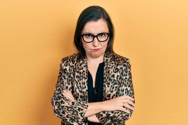 Middle age hispanic woman wearing business clothes and glasses skeptic and nervous, disapproving expression on face with crossed arms. negative person. 