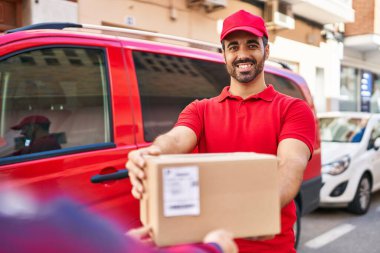Genç İspanyol kurye sokakta paket veriyor.