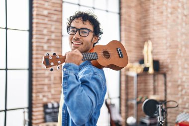 Genç İspanyol müzisyen müzik stüdyosunda ukulele tutuyor.