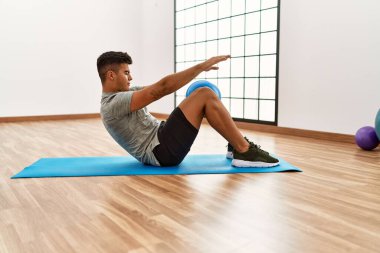 Spor merkezinde top kullanarak karın kaslarını çalıştıran genç bir İspanyol.