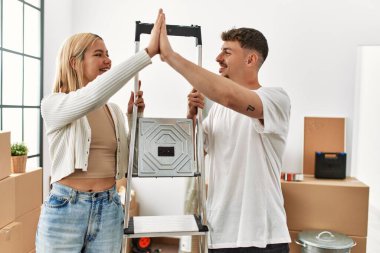 Kafkasyalı genç çift yeni evinde işçi merdivenlerini tutarken beşlik çakıyor..