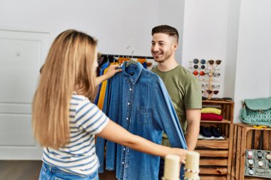 Genç İspanyol çift gülümsüyor, mağazadan kıyafet seçerken mutlular..