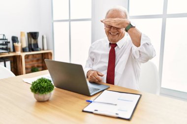 Senior man working at the office using computer laptop covering eyes with hand, looking serious and sad. sightless, hiding and rejection concept 