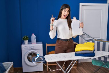 Çamaşırlarını katladıktan sonra ütüleyen esmer kadın bir fikre ya da soru işaretine şaşırdı ve mutlu bir yüzle işaret etti. 