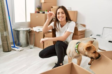 Genç İspanyol kadın gülümsüyor. Yeni evin anahtarını elinde tutuyor.