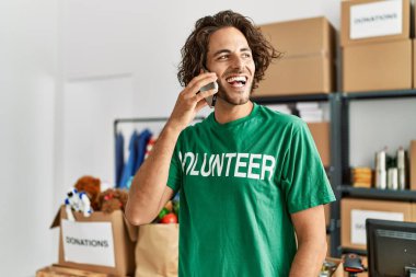 Genç İspanyol gönüllü adam gülümsüyor. Yardım merkezindeki akıllı telefondan konuşuyor..