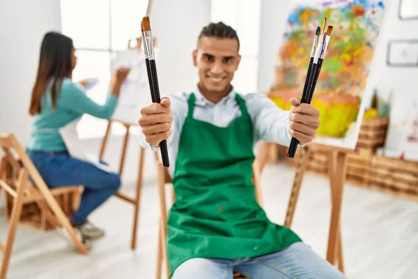 年轻的拉丁画家夫妇在艺术工作室里开心地微笑着绘画 — 图库照片