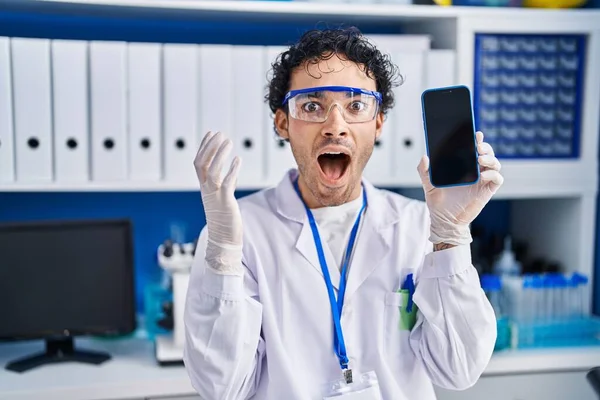 Hispanic Man Arbetar Forskare Laboratorium Visar Smartphone Skärmen Firar Seger — Stockfoto