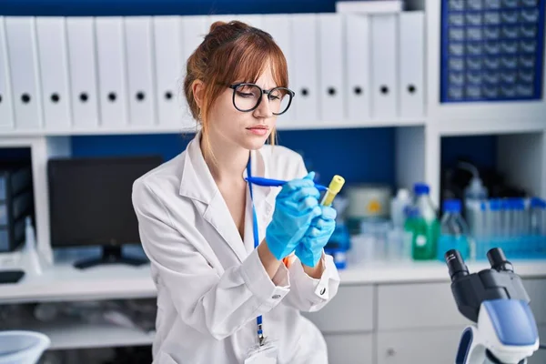 Young woman scientist write on test tube at laboratory