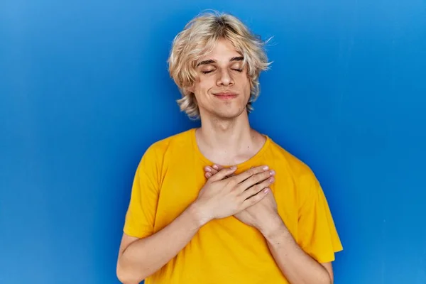 Jovem Homem Moderno Sobre Fundo Azul Sorrindo Com Mãos Peito — Fotografia de Stock