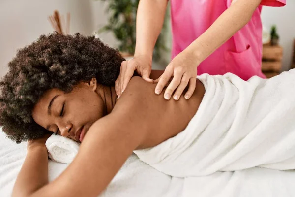 Young african american woman having back massage at beauty center