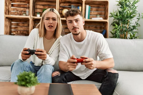 Young caucasian couple concentrated playing video game at home.