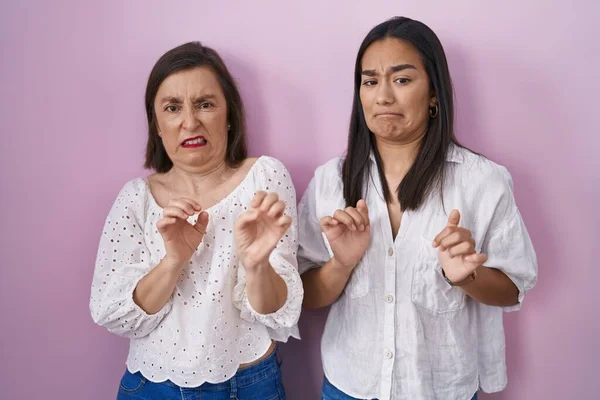 Hispanic mother and daughter together disgusted expression, displeased and fearful doing disgust face because aversion reaction.