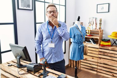 Middle age man working as manager at retail boutique bored yawning tired covering mouth with hand. restless and sleepiness. 