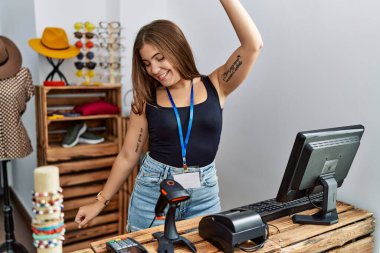 Genç esmer kadın perakende dükkanında açık mesajla pankart tutuyor mutlu ve neşeli dans ediyor, gülümsüyor rahat ve kendinden emin bir şekilde müzik dinliyor. 