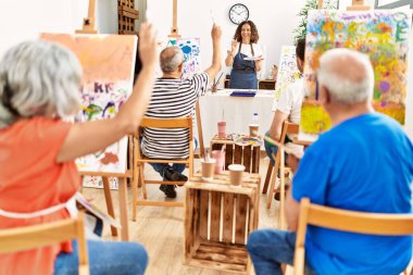 Bir grup orta yaşlı öğrenci resim stüdyosunda resim dersi alıyor..